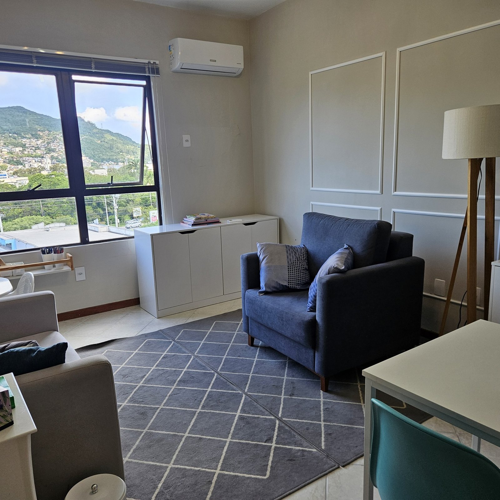 Sala de atendimento com poltrona, mesa de trabalho e vista para as montanhas de Florianópolis