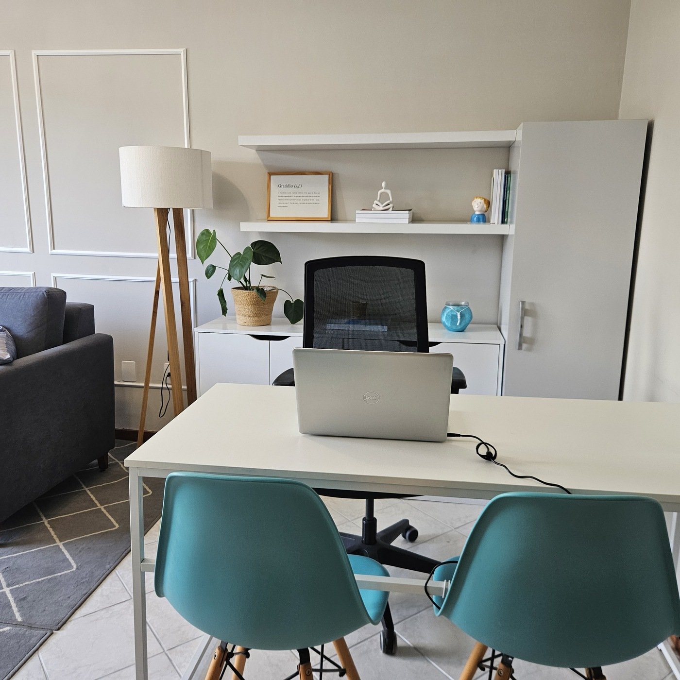 Mesa de atendimento do consultório com notebook e estante decorada