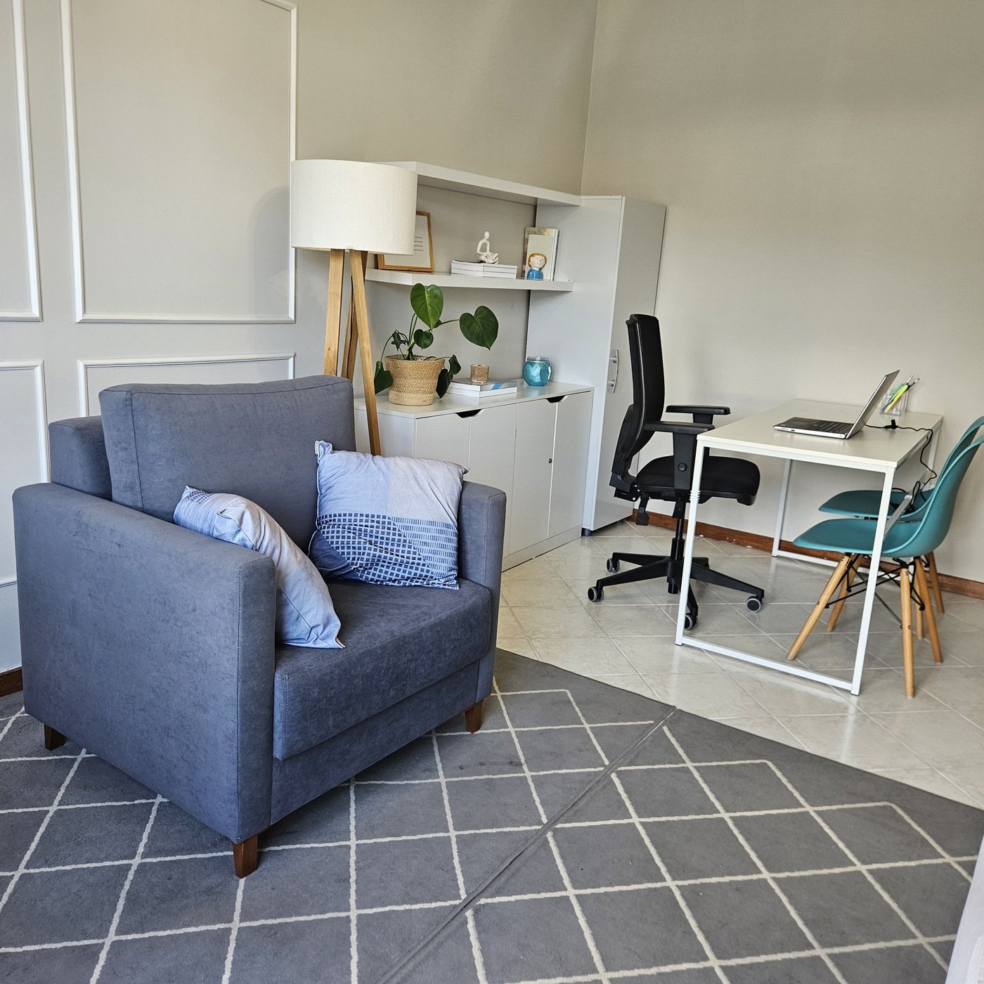 Poltrona de atendimento com estante, luminária e mesa ao fundo